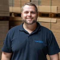 Mann mit blauem T-Shirt in einer Lagerhalle 